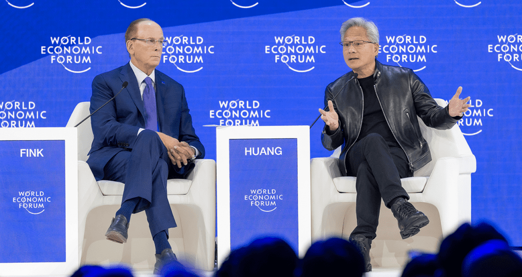 Jensen Huang and Larry Fink speaking on stage at the World Economic Forum during a fireside chat on artificial intelligence.