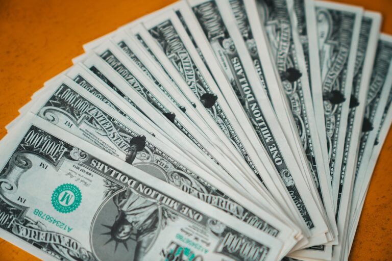 Stack of US one million dollar novelty bills fanned out on an orange surface