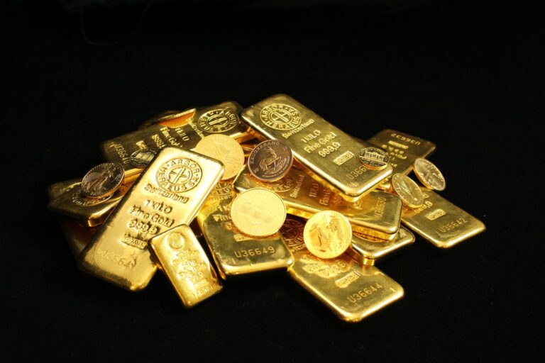 Pile of gold bars and coins on a black background.