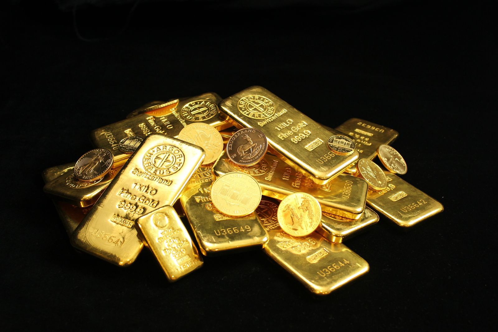 Pile of gold bars and coins on a black background.