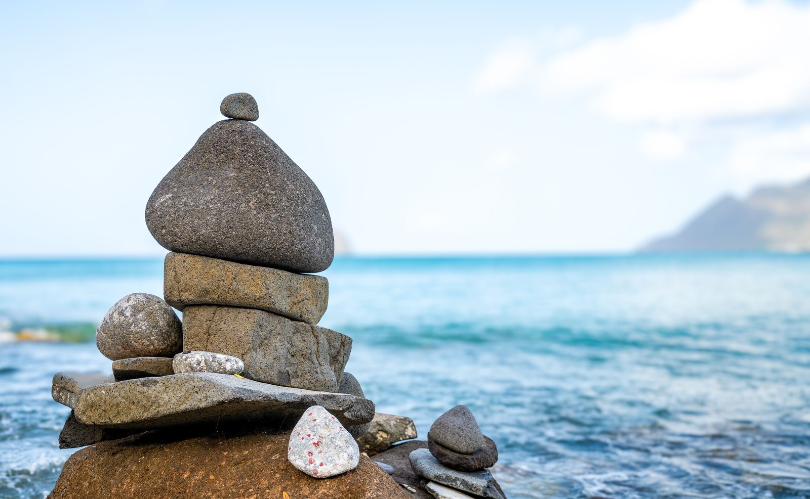 Balanced stack of stones by the water, representing the trade-off between stock growth and bond stability