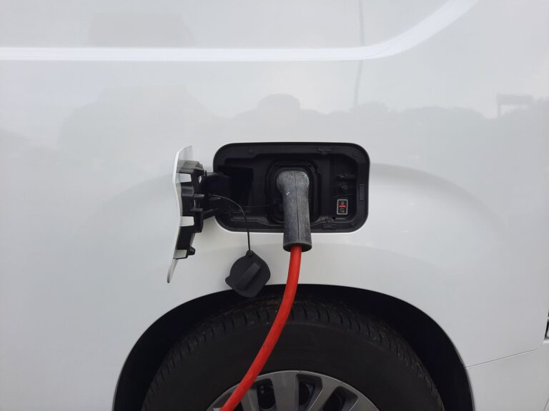 Red charging cable plugged into the charging port of a white electric vehicle