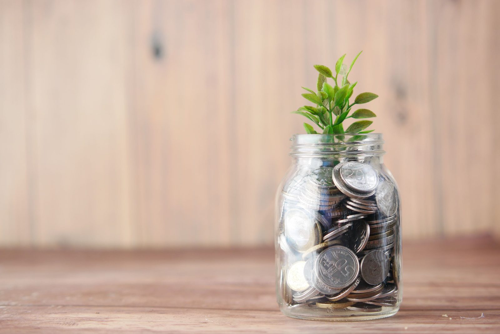 Glass jar of coins with a green sprout growing from the top, representing HSA contributions growing under the 2026 and 2027 limits
