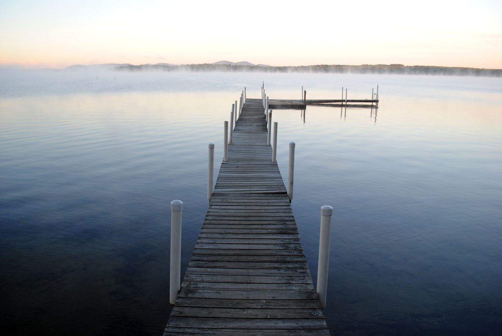 Wooden dock reaching into a calm, misty lake at sunrise, representing an HSA as a long-term retirement healthcare fund