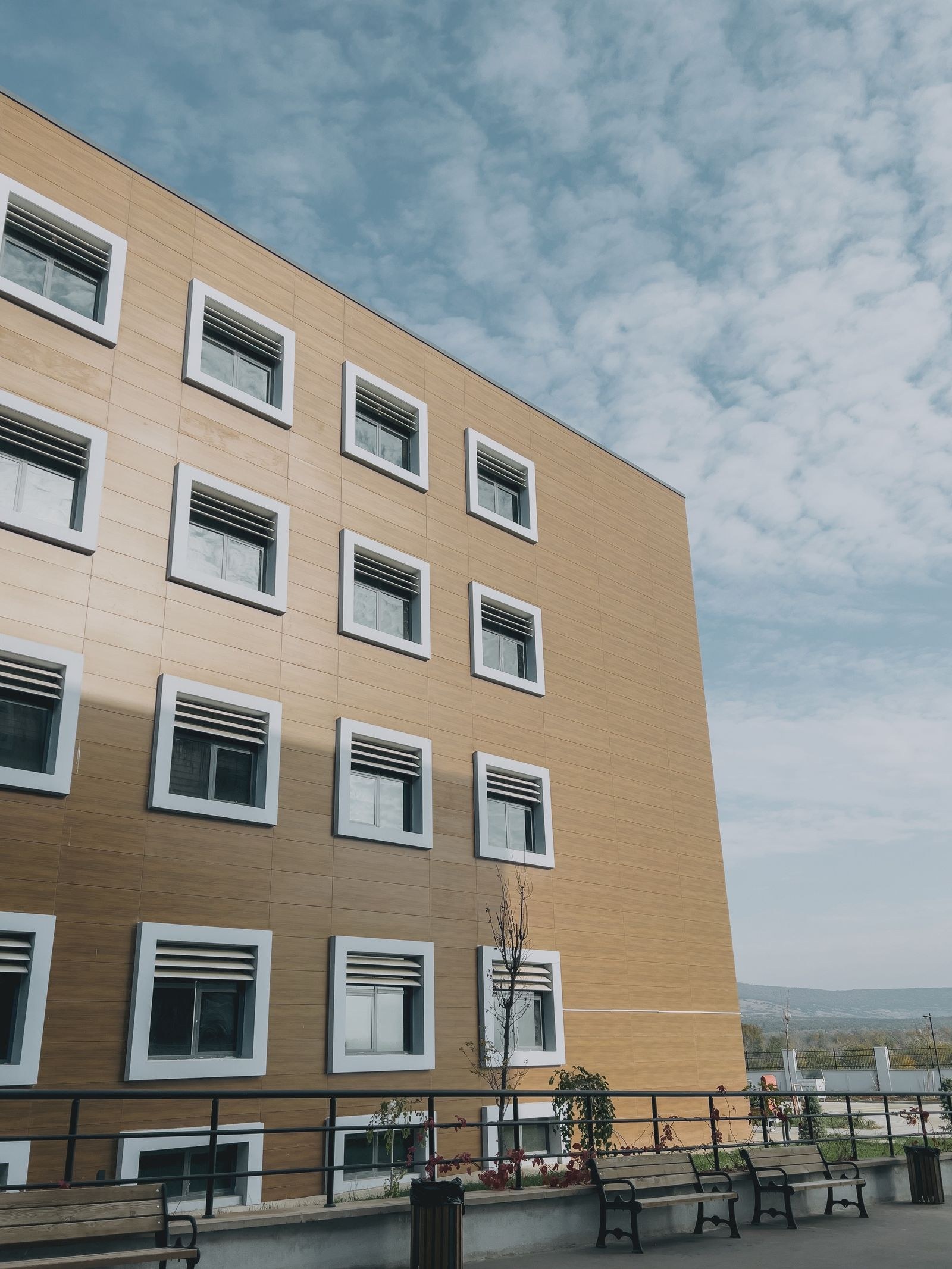 Modern hospital building exterior with a tan paneled facade and white-framed windows