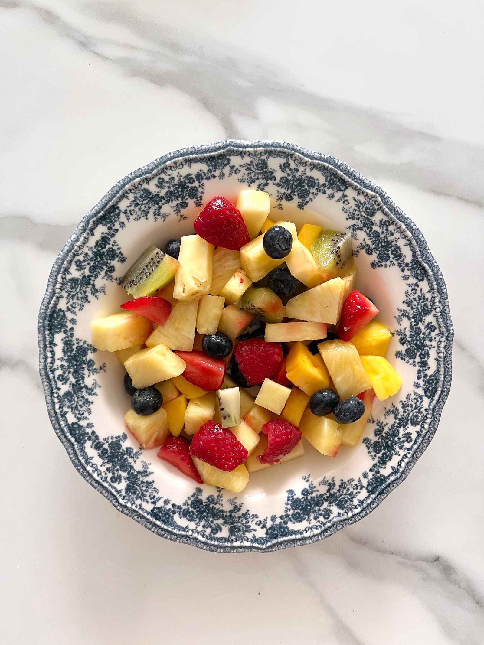 Colorful mixed fruit salad in a blue patterned bowl from above, symbolizing a pooled index portfolio of many holdings
