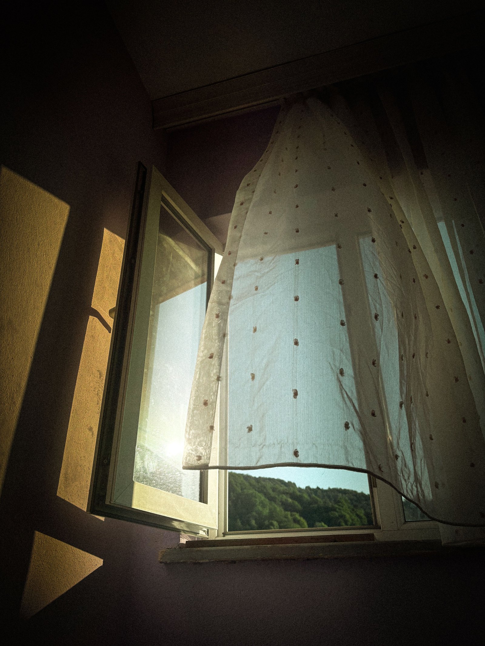 Open window with a sheer curtain billowing in sunlight, representing taxable account exposure versus tax-advantaged shelter