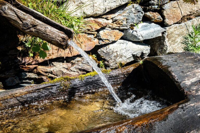 Clear water flowing in a steady stream from a wooden spout into a trough, a metaphor for required minimum distributions from retirement savings