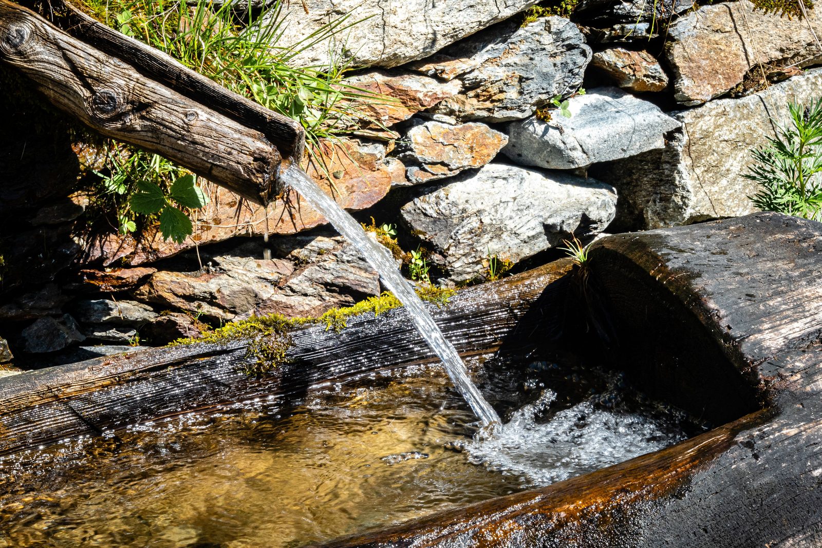 Clear water flowing in a steady stream from a wooden spout into a trough, a metaphor for required minimum distributions from retirement savings