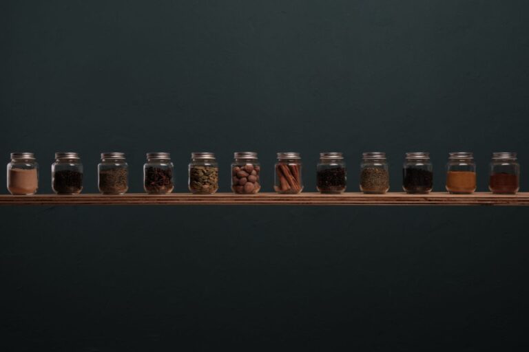 Row of glass spice jars on a wooden shelf representing stock market sectors as separate portfolio ingredients