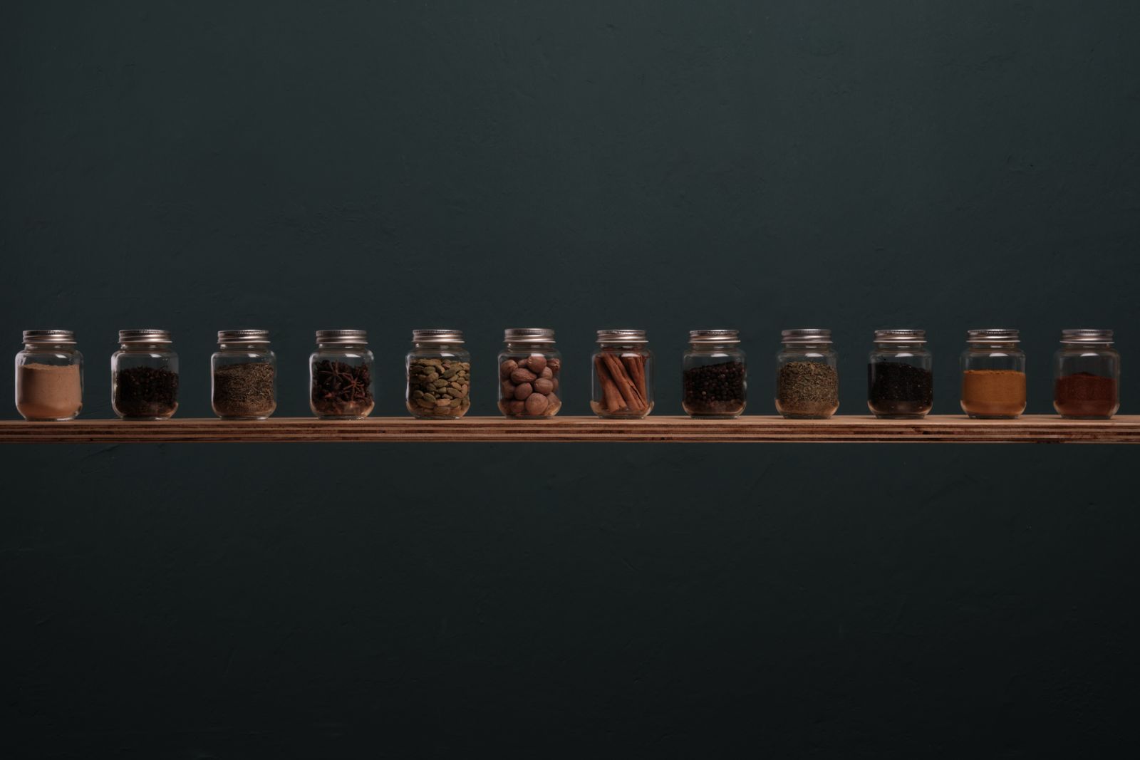 Row of glass spice jars on a wooden shelf representing stock market sectors as separate portfolio ingredients
